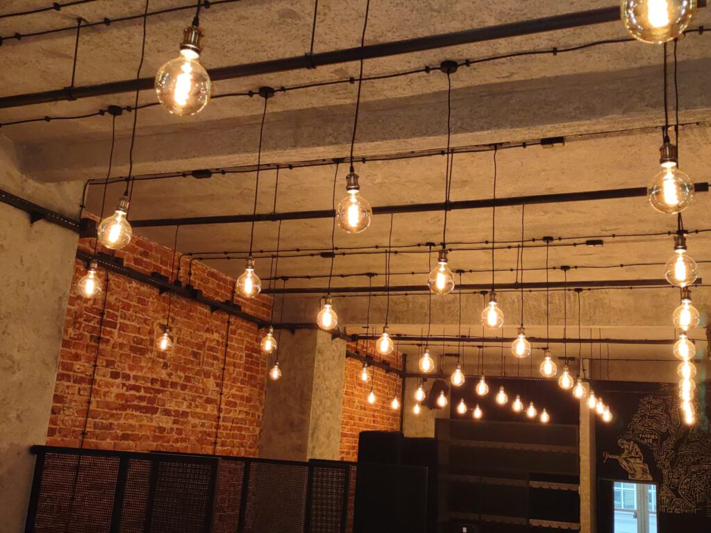 Żarówki wiszące w loftowej przestrzeni z ceglaną ścianą.
